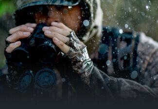 Hunter in the rain holding Bushnell Binoculars