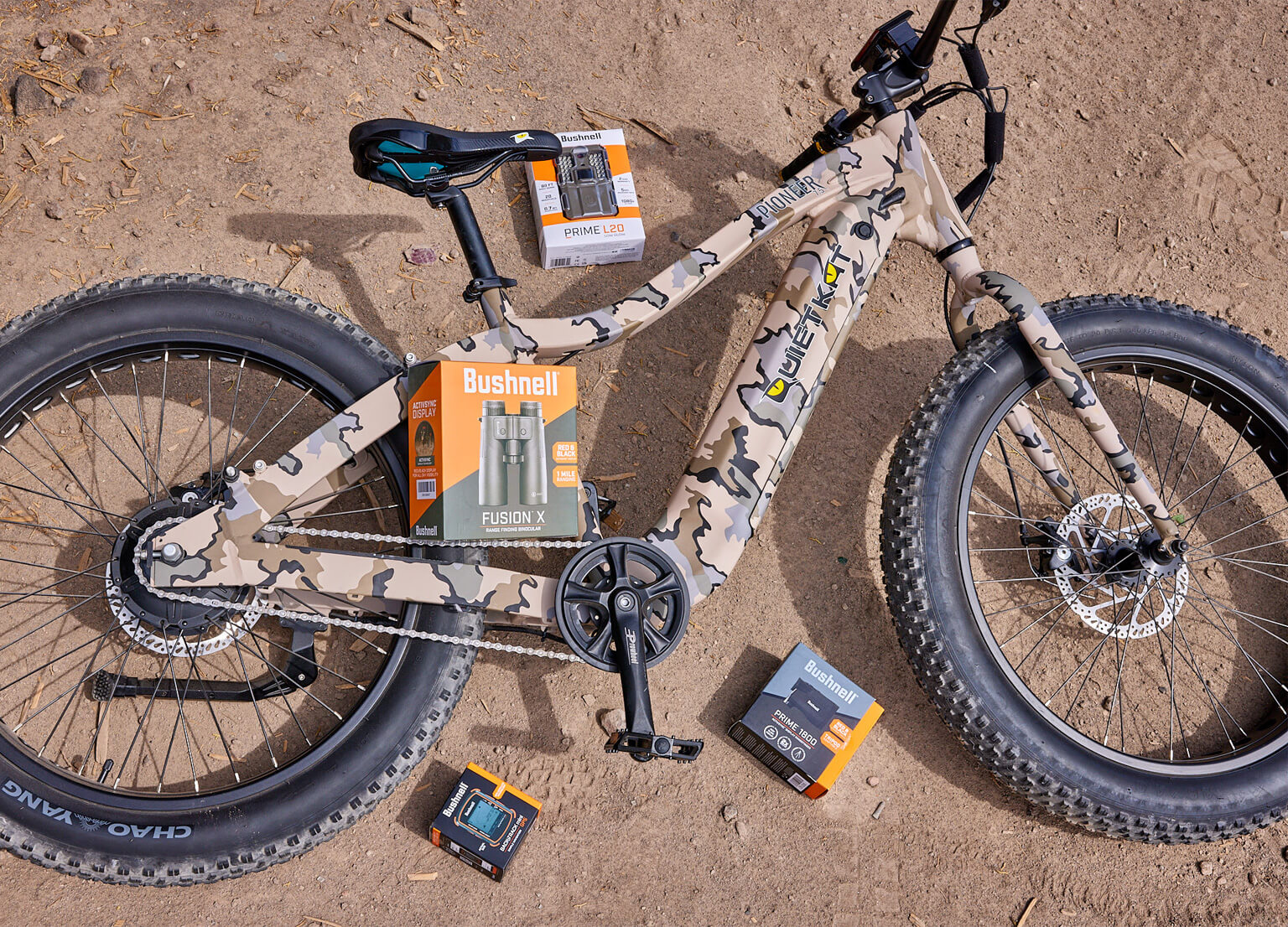 Group shot of sweepstakes items including QuietKat Pioneer 750W e-bike, Bushnell Fusion X binoculars, Bushnell Prime 1800 Rangefinder, 6 Bushnell Prime L20 Low Glow Trail Cameras, Bushnell BackTrack Mini GPS